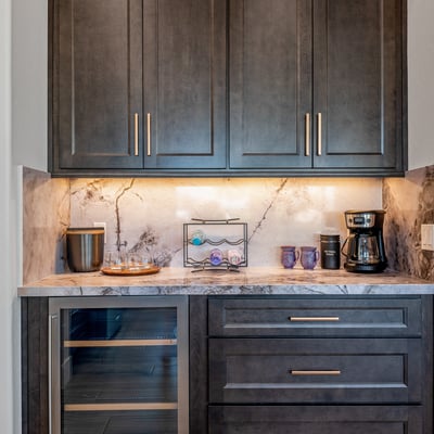 Built-in coffee and beverage bar with wine fridge and marble backsplash provides convenience and style in the kitchen area.