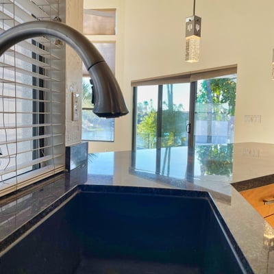 Beautiful granite countertop and stainless faucet positioned to overlook the pool and lake views through bright, open windows.