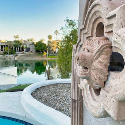 Hand-carved stone fountain detail enhances the backyard s peaceful lakeside setting with timeless artistry.