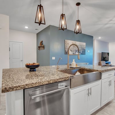 Contemporary pendant lights accent the large island and farmhouse sink, enhancing the kitchen s modern feel and energy-efficient layout in Litchfield Park.