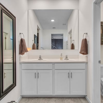 A bright dual-vanity bathroom with fresh cabinetry, large mirror, and soft recessed lighting delivering modern efficiency in Litchfield Park.