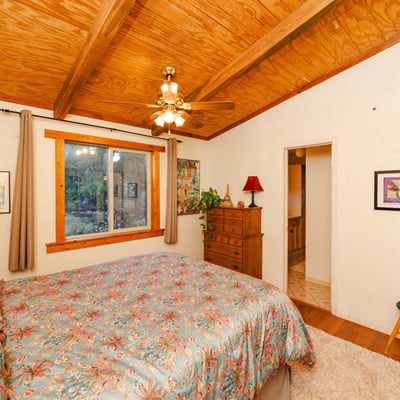 This restful primary bedroom showcases warm wood ceilings, soft textures, and scenic outdoor views. Its rustic charm reflects the essence of quiet living in Hackberry s desert landscape.