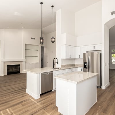 Open Scottsdale interior connecting the kitchen and living room with vaulted ceilings and modern flooring throughout. Built-in shelving and a fireplace create a warm focal point for everyday living.