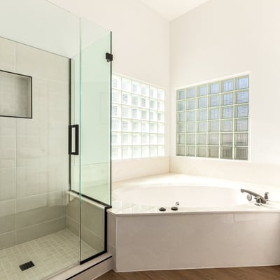 Relaxing Scottsdale bathroom featuring a glass walk-in shower and large soaking tub surrounded by natural light from glass block windows. Modern finishes create a luxurious atmosphere.