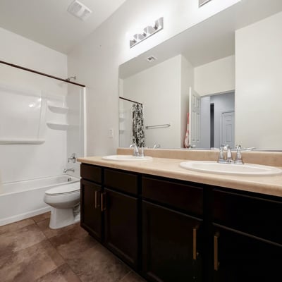 Well-appointed guest bath with dual sinks, full tub and shower, and tile flooring, offering comfort and functionality for family or guests.