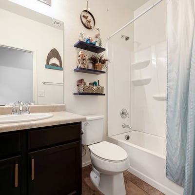 Guest bathroom with tub and shower combination, tile flooring, and dark cabinetry for a polished, functional space.
