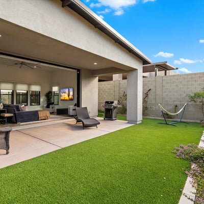 Backyard designed for entertaining with sliding glass doors, patio space, and turf lawn. Enjoy seamless indoor-outdoor living in Scottsdale.