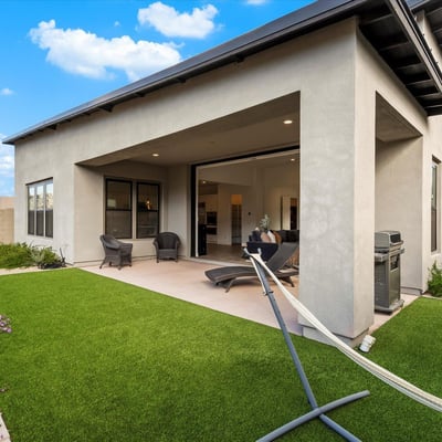 Thoughtfully designed backyard with turf, patio seating, and modern exterior lines. A perfect retreat in this Scottsdale luxury home.