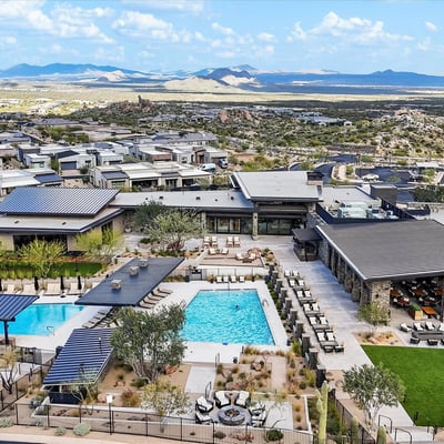 Aerial view of the Sereno Canyon community center showcasing multiple pools, outdoor gathering spaces, and luxury amenities surrounded by desert terrain.