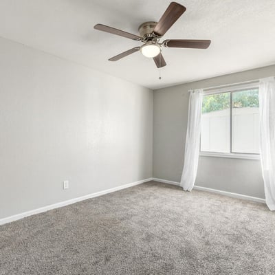 Bright primary bedroom with soft carpet, neutral finishes, and a ceiling fan an inviting retreat in this updated Phoenix home with a comfortable layout.