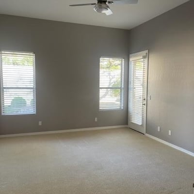 Bright bedroom with large windows, soft carpeting, and ceiling fan. Ideal for restful nights and flexible furniture placement.