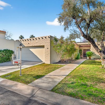 Clean, well-kept front exterior with attached garage, private walk-up entry, and manicured landscaping inside a secure Phoenix community.