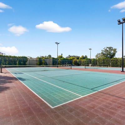 Community tennis courts surrounded by mature landscaping, offering a convenient recreational option just moments from home.