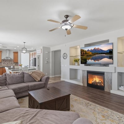 Stylish living area featuring a fireplace with decorative niches, ceiling fans, and durable wood-style flooring throughout the main living space.