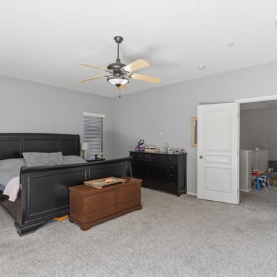 Generous primary suite featuring plush carpeting, large windows, ceiling fan, and ample space for bedroom furniture, creating a peaceful retreat in this Queen Creek property.