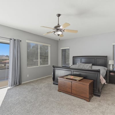 Beautiful primary bedroom with sliding glass doors leading to a private balcony, allowing fresh air and scenic neighborhood views.