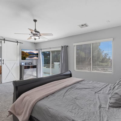Spacious primary bedroom with plush carpet, ceiling fan, and neutral tones, offering a relaxing retreat within this well-designed Queen Creek home.