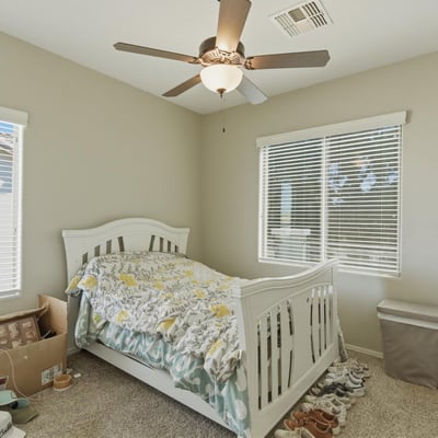 Comfortable secondary bedroom with plush carpet, ceiling fan, and large windows that bring in natural light, creating a welcoming space for guests or family.