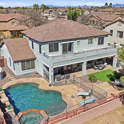 Drone perspective highlighting the backyard retreat with pool, spa, covered patio seating, and landscaped outdoor entertaining areas.