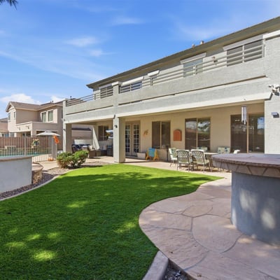 Private backyard retreat with artificial turf lawn, shaded patio seating, and fenced pool and spa area providing a perfect outdoor living space in this Queen Creek home.
