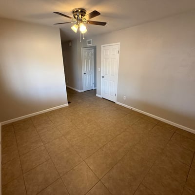 Spacious bedroom featuring tile floors, ceiling fan, and clean neutral finishes. The layout allows flexible use as a bedroom, office, or hobby room.