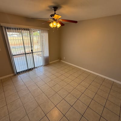 Generous bedroom layout with ceiling fan, tile flooring, and closet access. The neutral palette creates a comfortable and versatile living space.