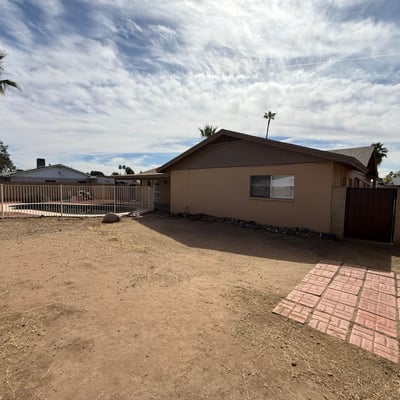 Rear exterior view highlighting the covered patio, fenced pool, and spacious yard. The layout provides a welcoming outdoor setting ideal for relaxing evenings and weekend gatherings.
