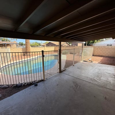 Covered backyard patio offering shade and direct views of the fenced pool area. This outdoor living space is perfect for entertaining guests or enjoying peaceful afternoons.