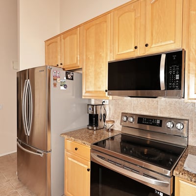Cooking area with stainless steel range, built-in microwave, and tiled backsplash. This Phoenix home includes updated features and efficient layout.