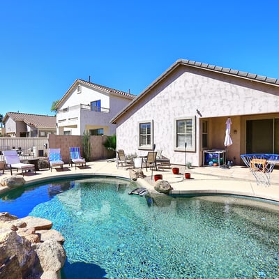 Backyard with Pebble Tec pool, rock waterfall feature, and spacious patio. This Phoenix home highlights outdoor living with low-maintenance desert landscaping.