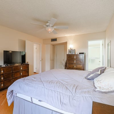 Spacious primary bedroom featuring neutral finishes, hardwood floors, and convenient access to the ensuite bath.