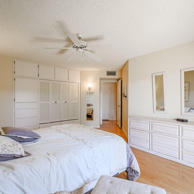 Secondary bedroom with built-in cabinets, hardwood floors, and ample closet space, ideal for guests or flexible living needs.