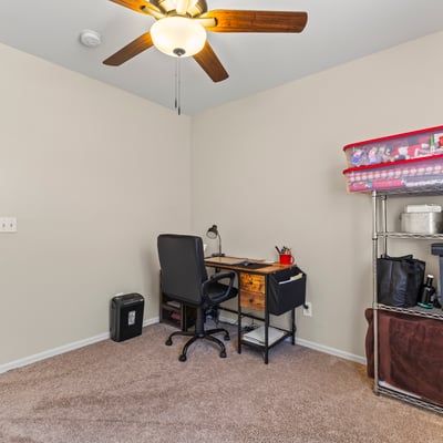 Multi-use room perfect for a home office or bedroom, featuring natural light, neutral tones, and ceiling fan.