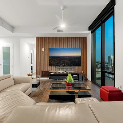 Stylish great room with expansive glass walls, modern finishes, and sweeping Phoenix skyline views, creating a bright and inviting living space.