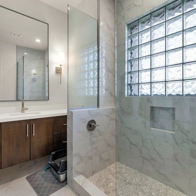 Well-appointed bathroom with dual sinks, updated cabinetry, and glass block accents for natural light in this Phoenix home.