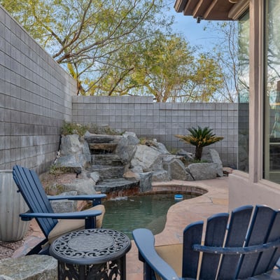Serene backyard featuring a cascading water feature, patio seating, and low-maintenance landscaping in this Phoenix home.