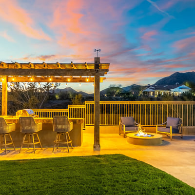 Stylish outdoor entertaining area with built-in kitchen, bar seating, and fire pit, set against scenic Scottsdale mountain views.
