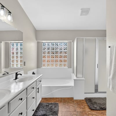 Bright primary bathroom with dual vanities, soaking tub, and walk-in shower. Functional layout offers everyday comfort in this Casa Grande property.