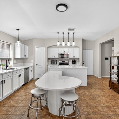 Functional kitchen with breakfast bar, white cabinets, and modern appliances. Seamless connection to living areas enhances flow in this Casa Grande home.