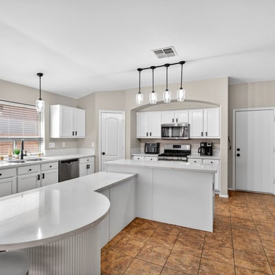 Bright open kitchen with large island, white cabinetry, and modern lighting. Perfect for entertaining and daily living in this Casa Grande home.