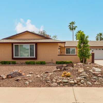 Front exterior with classic desert landscaping and mature greenery. This Sun City property highlights low-maintenance design and updated home features.