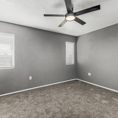 Comfortable bedroom featuring soft carpet, ceiling fan, and bright windows. This Sun City home offers updated finishes and inviting living spaces.