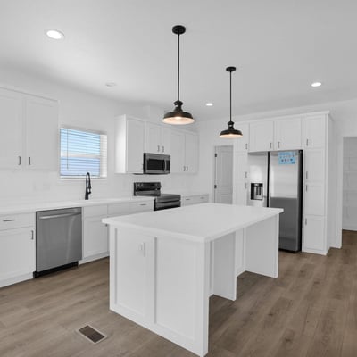 Modern kitchen with an oversized island, abundant cabinet storage, stainless steel appliances, and a walkthrough pantry. The clean design and generous workspace make meal preparation and entertaining effortless.
