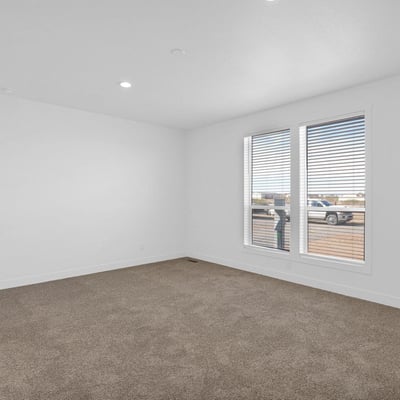 Comfortable primary suite offering generous dimensions, soft carpeting, and large windows that welcome natural light. A relaxing space designed for rest while enjoying peaceful desert surroundings.