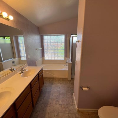 Generous primary bathroom featuring dual vanities, extensive countertop space, a soaking tub, and separate shower. A well-designed space that balances style and everyday practicality.