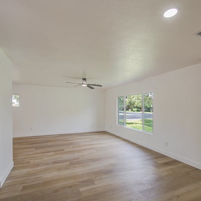 Bright and open, this remodeled living space features contemporary flooring, ceiling fan, recessed lighting, and oversized windows for comfortable everyday living.