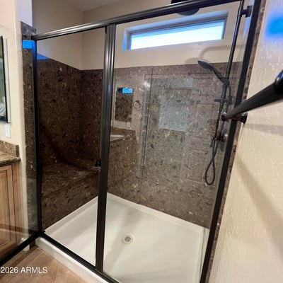 Luxurious walk-in shower with stylish tile surrounds, built-in bench seating, black framed glass enclosure, and upgraded shower fixtures creating a sophisticated spa-like experience.