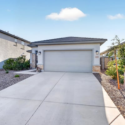 Charming front exterior showcases modern architecture, stone accents, desert landscaping, and a spacious attached garage, delivering outstanding curb appeal in Surprise.
