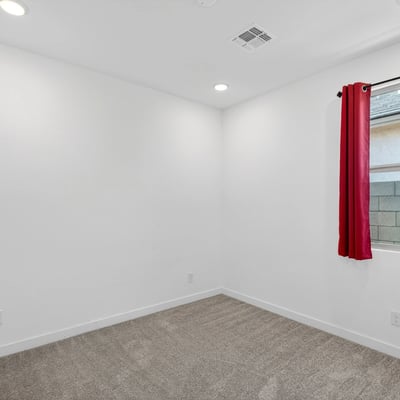A bright guest bedroom with plush carpet, recessed lighting, and a large window provides comfortable accommodations while complementing the home's open and modern design.