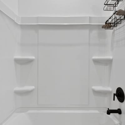 This updated bathroom includes a spacious tub and shower combination with contemporary matte black fixtures, built-in storage shelves, and low-maintenance finishes.